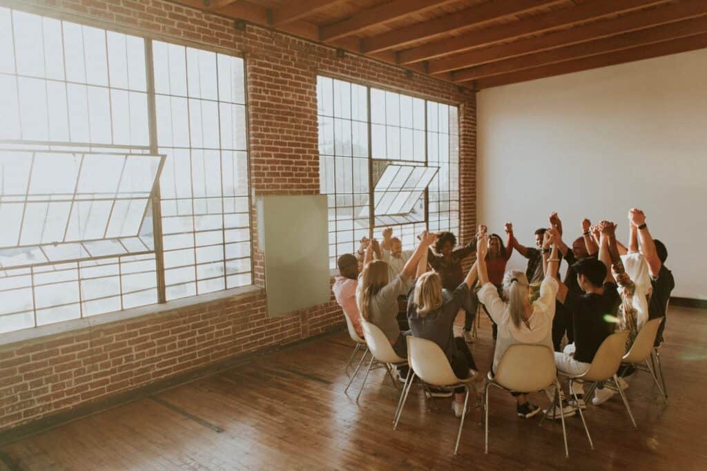 Diverse group of people holding hands in a circle during team-building activity at Sierra Vista coworking space.
